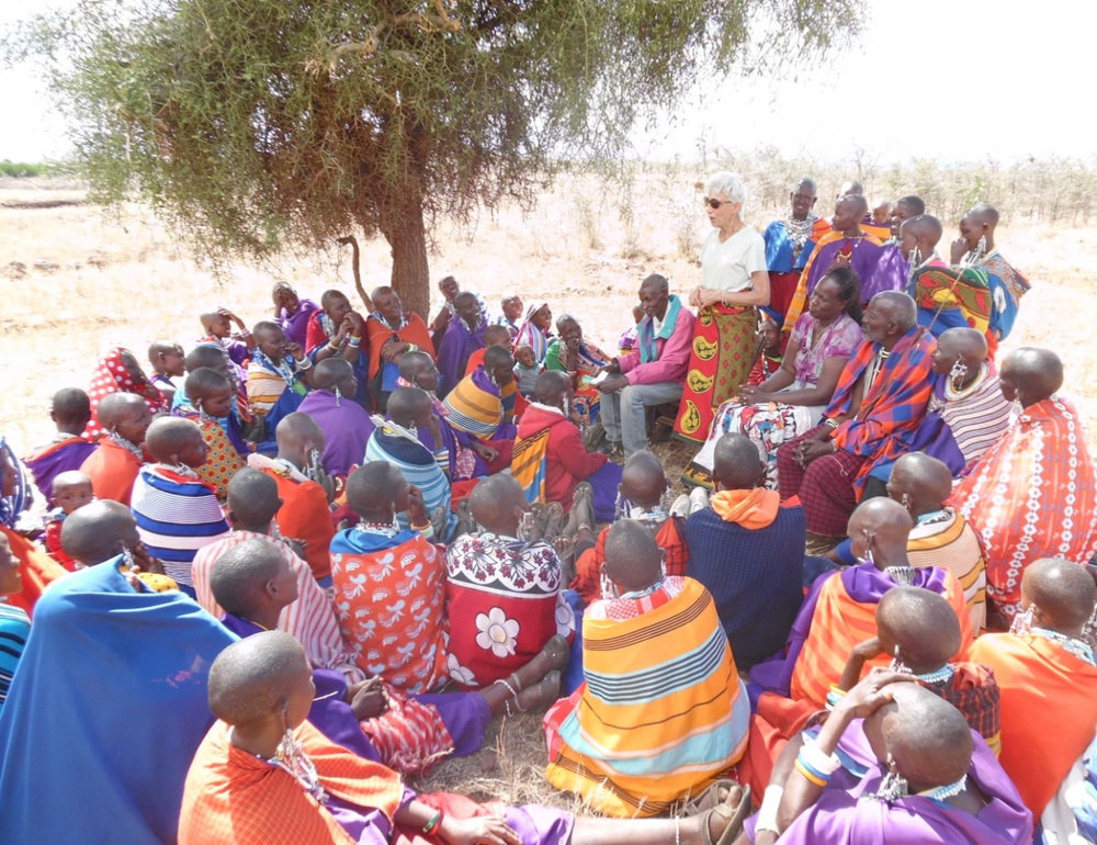 Sister Sue Rech speaking with a Maasai community gathered under a tree in Tanzania